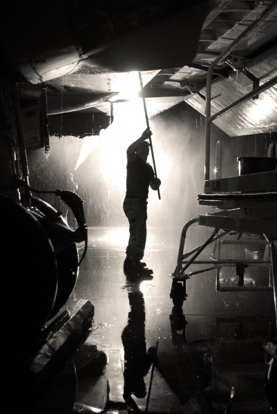 US Navy 090903-N-2102J-098 Aviation Electronics Technician 3rd Class Sean Robertson, from Portland, Oregon, washes the underside of a wing on a P-3 Orion on the flightline at Ali Air Base, Iraq