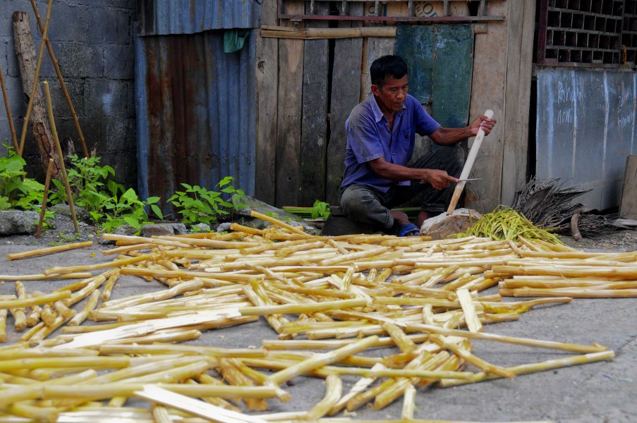 Filipino man shaving wood for rice cooking 080605-N-4128S-452